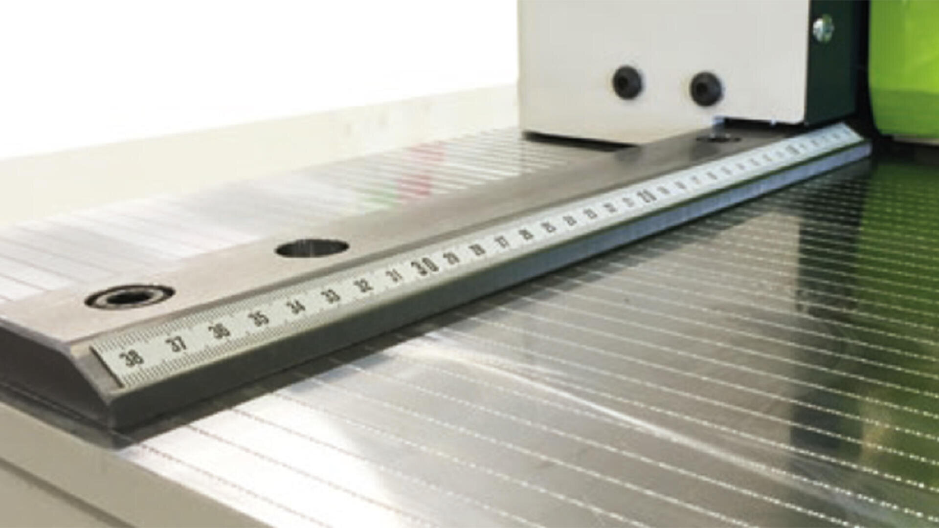 Nahaufnahme eines an einer Maschinenoberfläche befestigten Metalllineals mit Messmarkierungen von 28 bis 50 Zentimetern, Schrauben und einer reflektierenden, geriffelten Metallbasis.