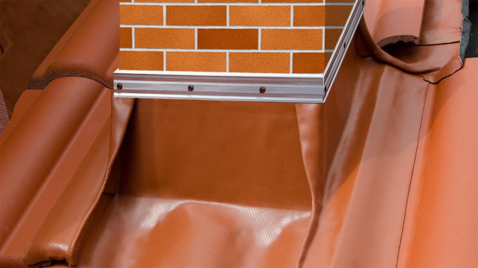 Close-up of a brick chimney with metal flashing installed at its base, surrounded by brown roofing material to provide a watertight seal where the chimney meets the sloped roof.