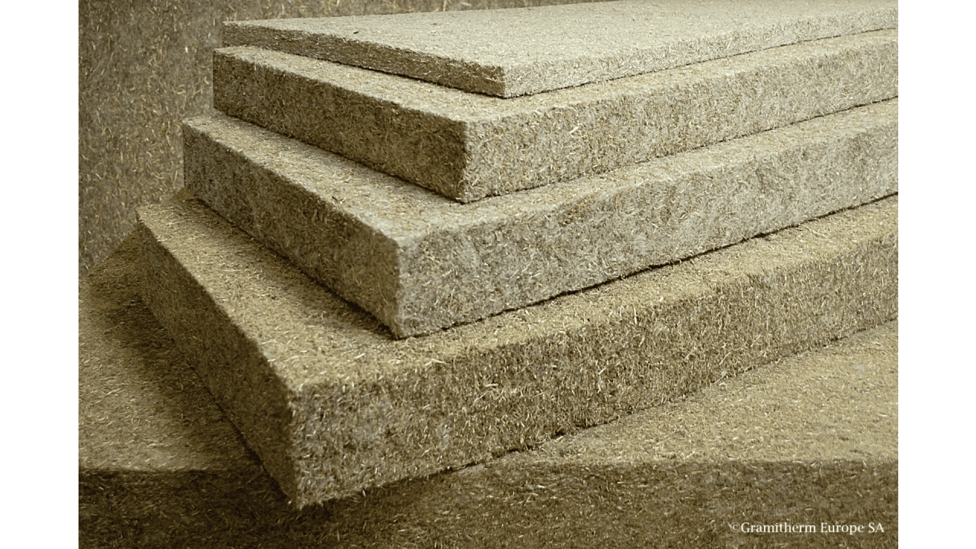 Several rectangular, stacked panels made of a fibrous, natural-looking material, possibly insulation boards, are shown in a close-up view. The texture appears rough and organic.