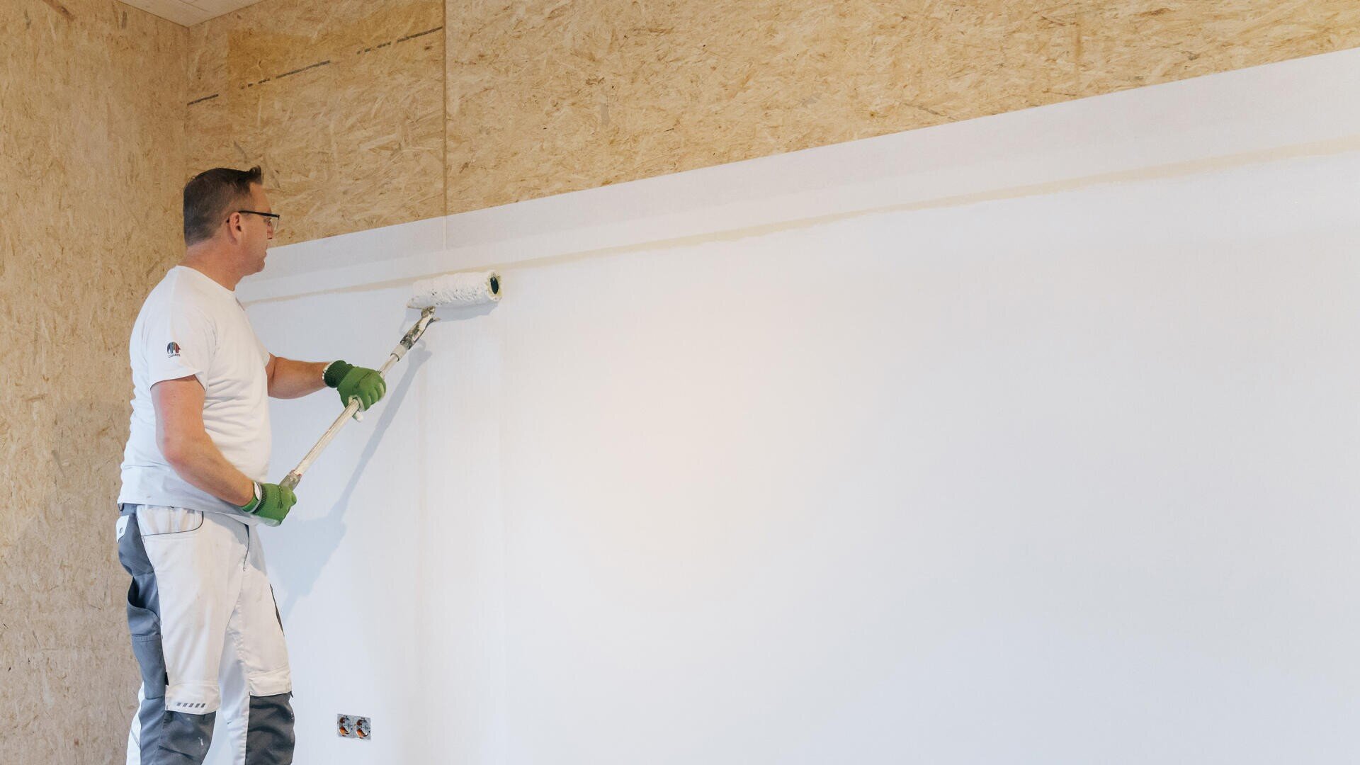 Eine Person beschichtet eine MAGNUMBOARD® OSB Evolution-Wand.