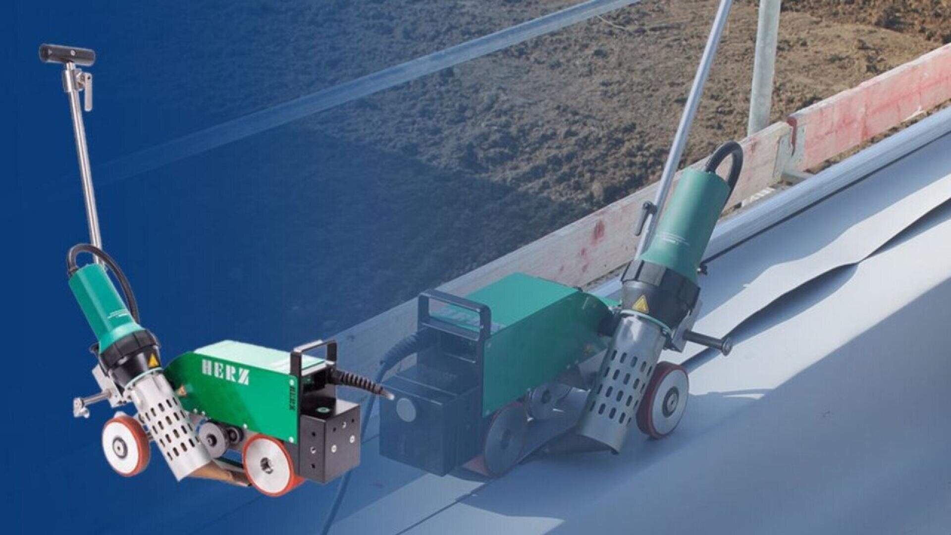 A green and silver industrial welding machine with wheels and a handle can be seen on a construction site, sealing sheets of material lying on the ground next to soil and wooden planks.