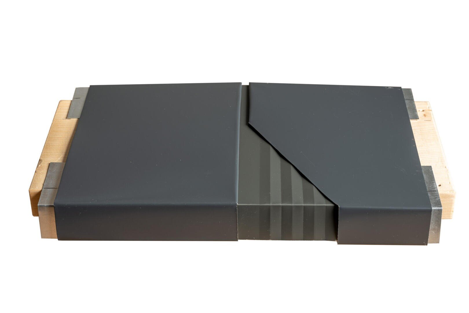 A rectangular wooden base supports two black rectangular panels, one of which is partially covered by a diagonally cut, overlapping black section with subtle vertical stripes.