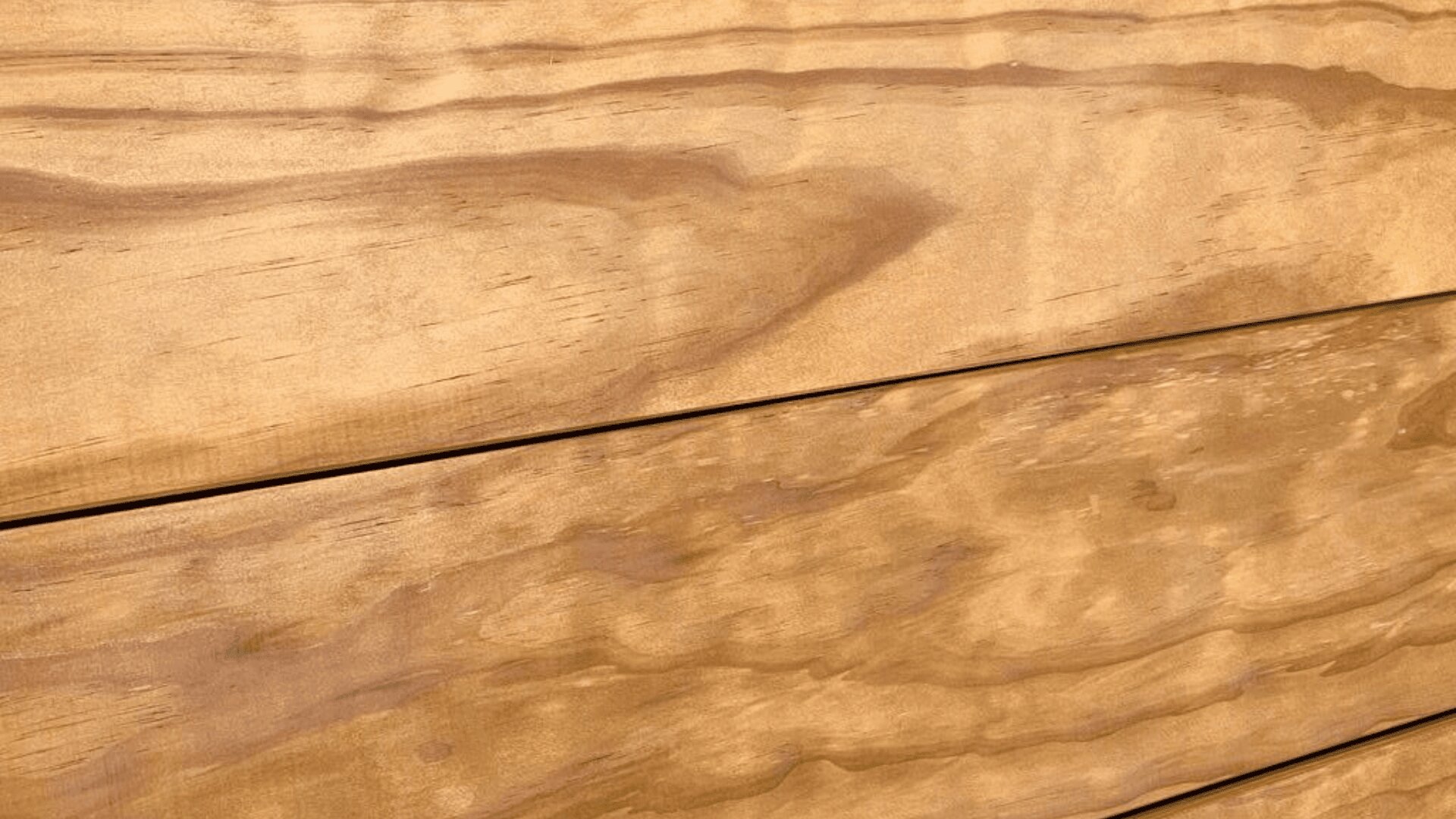 Nahaufnahme von Holzbrettern mit natürlicher Maserung und warmem Braunton. Das Bild zeigt die Textur und Linien des Holzes und betont sein organisches Aussehen und seine glatte Oberfläche.