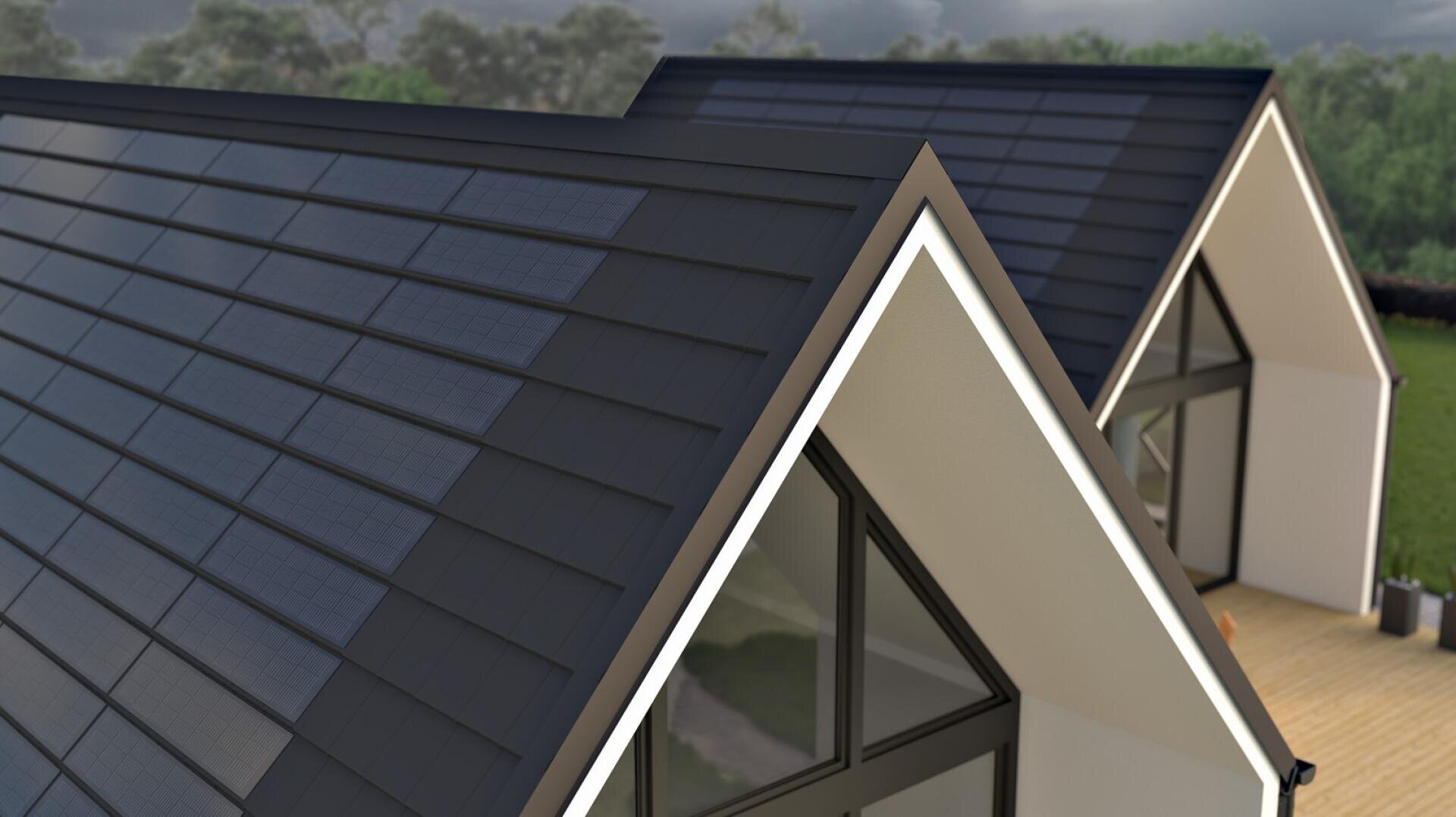 Modern houses with steep, triangular roofs covered with dark solar roof tiles. Large windows and a wooden outdoor terrace can be seen, with trees and a cloudy sky in the background.