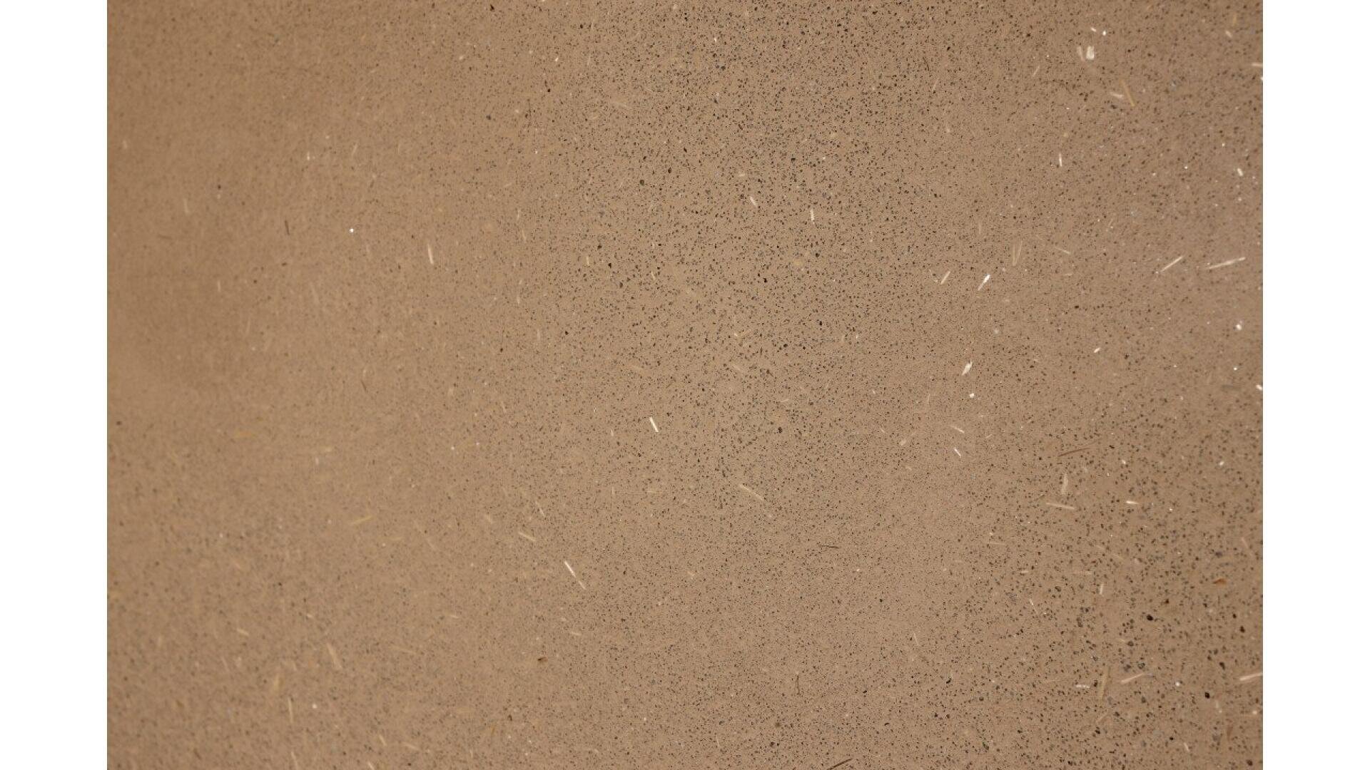 A close-up view of a smooth, textured brown concrete surface with small specks and faint markings scattered throughout.