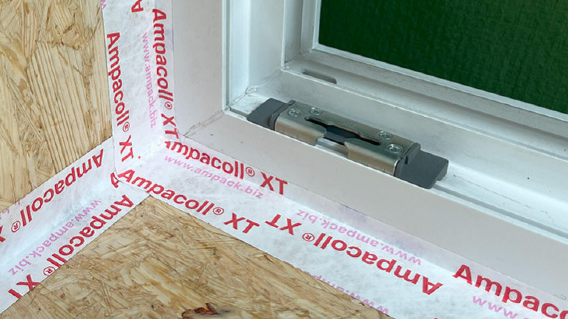 Nahaufnahme eines Fensterrahmens, der mit Ampacoll XT-Klebeband abgedichtet wird; das Klebeband wird sauber um den weissen Rahmen und die angrenzenden Holzflächen angebracht, um Luftdichtheit und Isolierung zu gewährleisten.