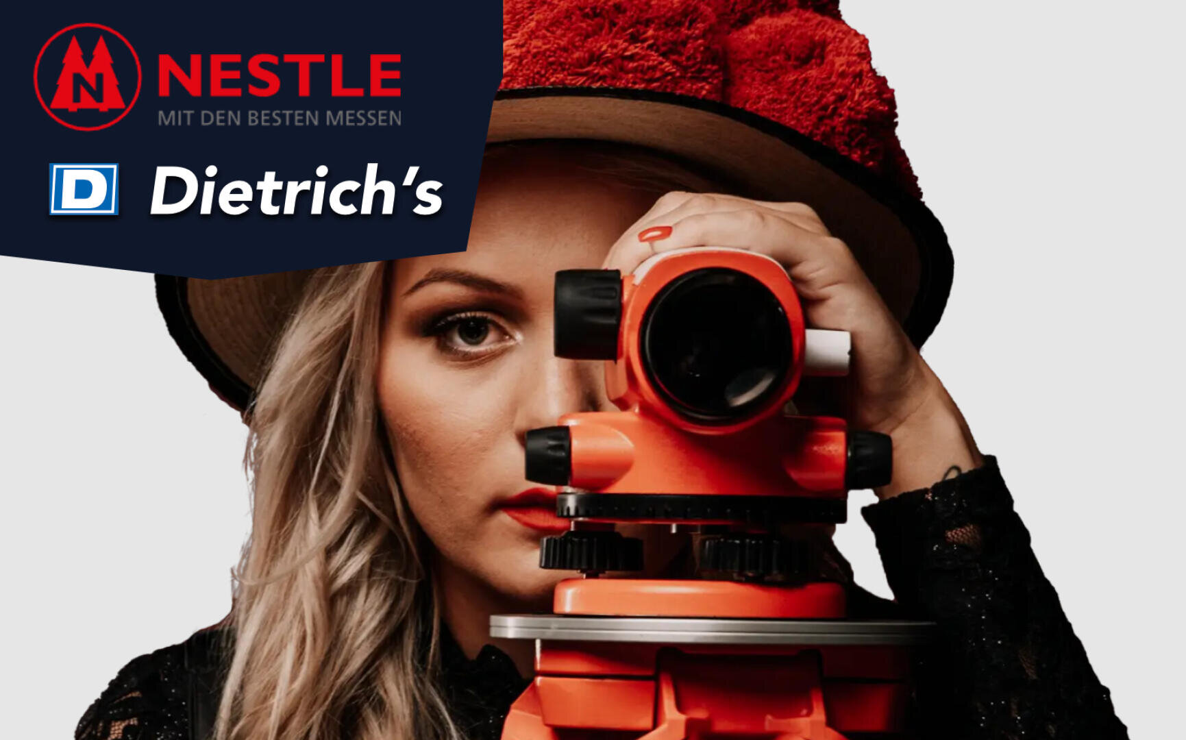 A woman with long blonde hair looks through an orange surveying instrument, wearing a red textured hat. The top left corner displays logos for Nestle and Dietrich’s with German text.