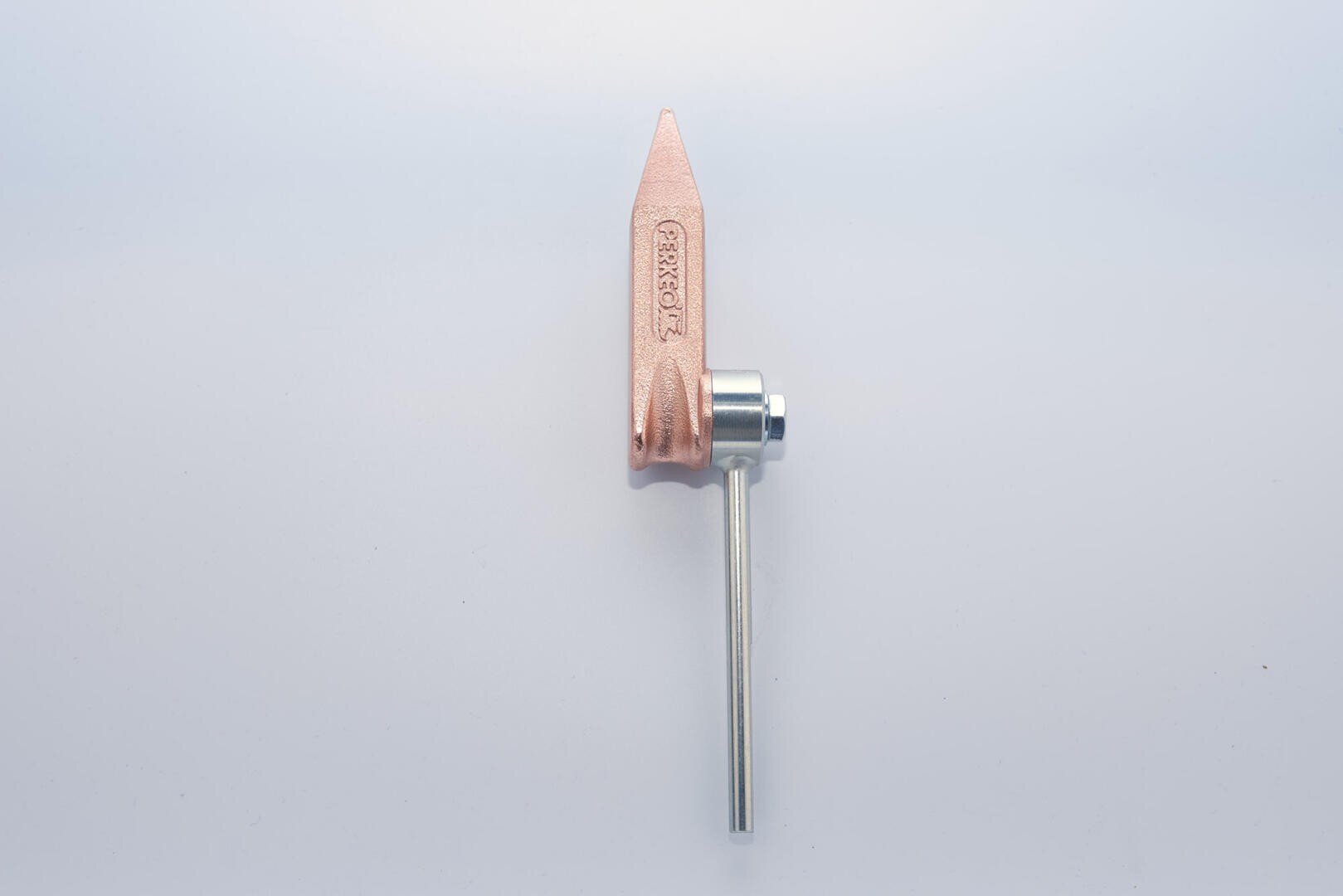 Eine kupferfarbene Erdungsklemme mit einer spitzen Spitze und einem daran befestigten Metallstab, vor einem weißen Hintergrund platziert.