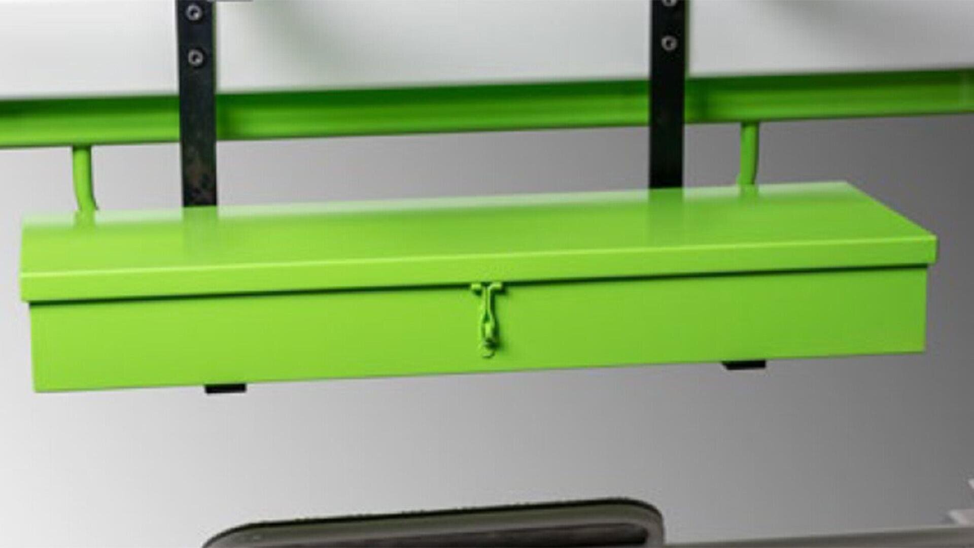 A rectangular, bright green metal box is mounted to a wall with black brackets. The box has a hinged lid secured by a simple front latch with a looped cord or lock.