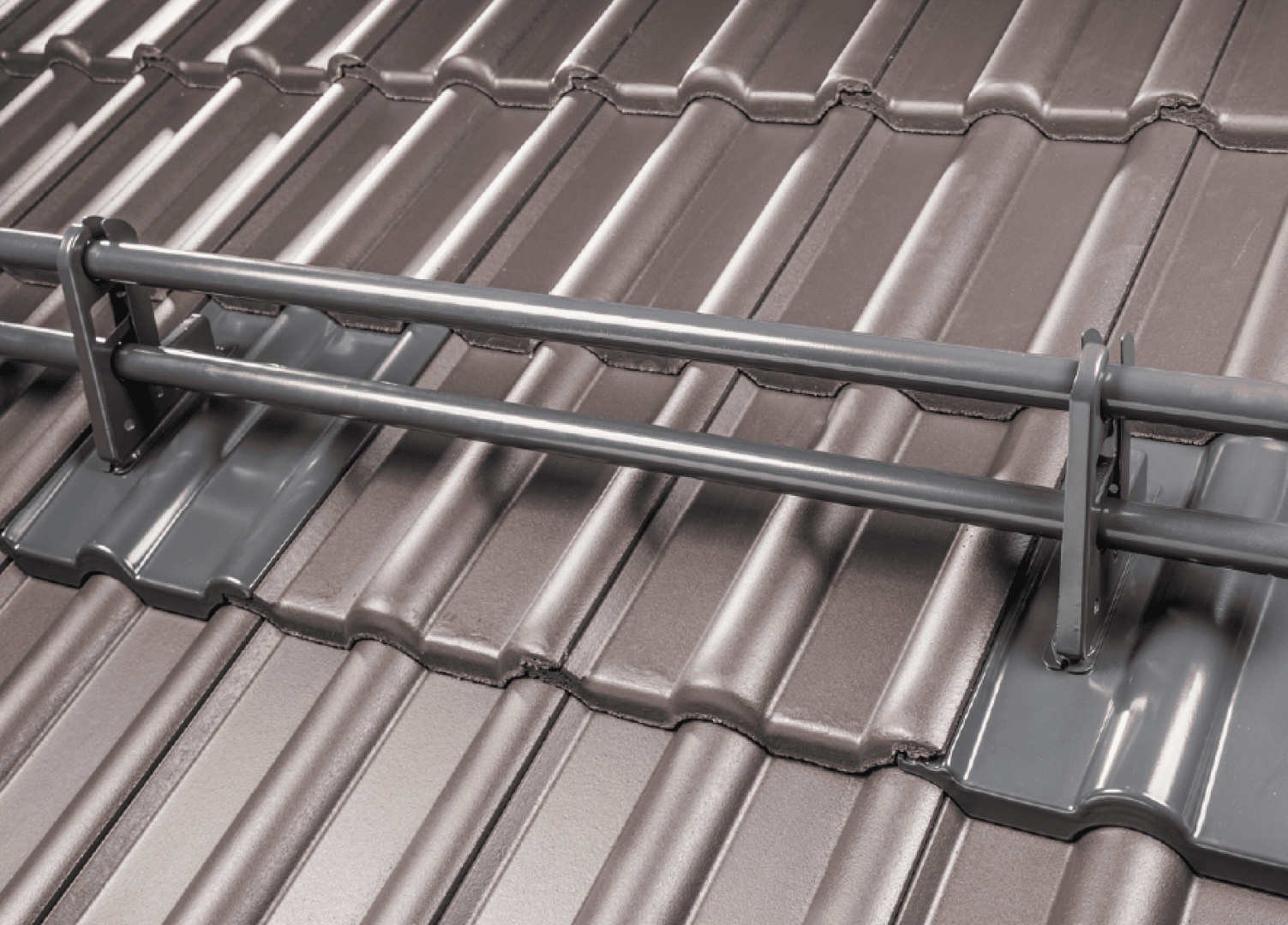 Nahaufnahme eines Schneefanggitters aus Metall, das auf einem braunen, gewellten Metalldach installiert wurde, um das Abrutschen von Schnee und Eis zu verhindern.